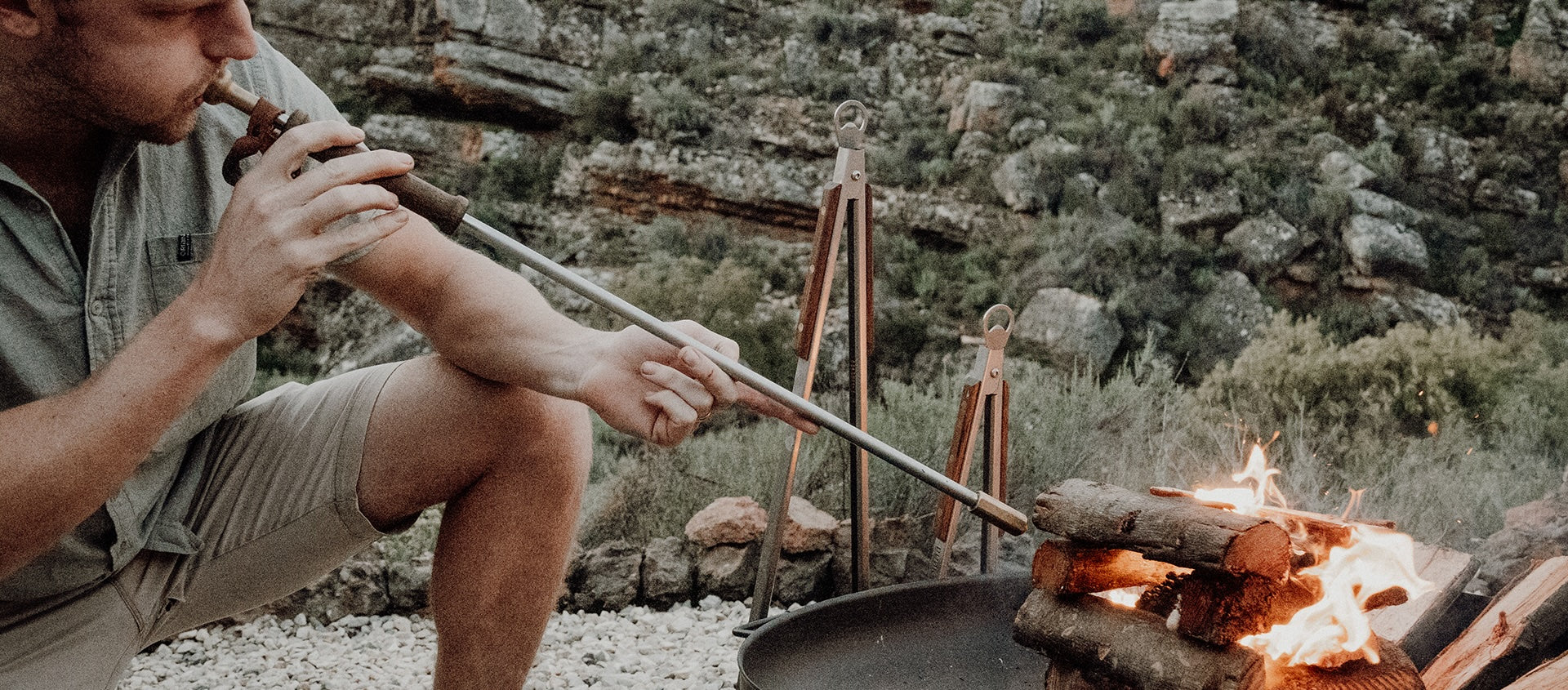 A man blowing towards a fire with his blower.
