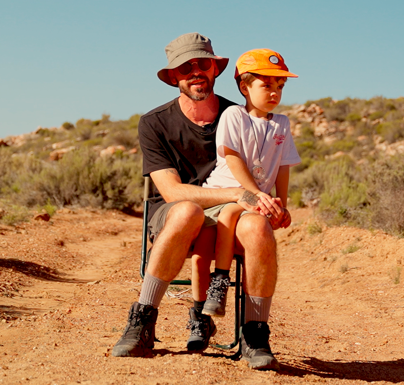Boy sitting on his dads lap in a rough terrain