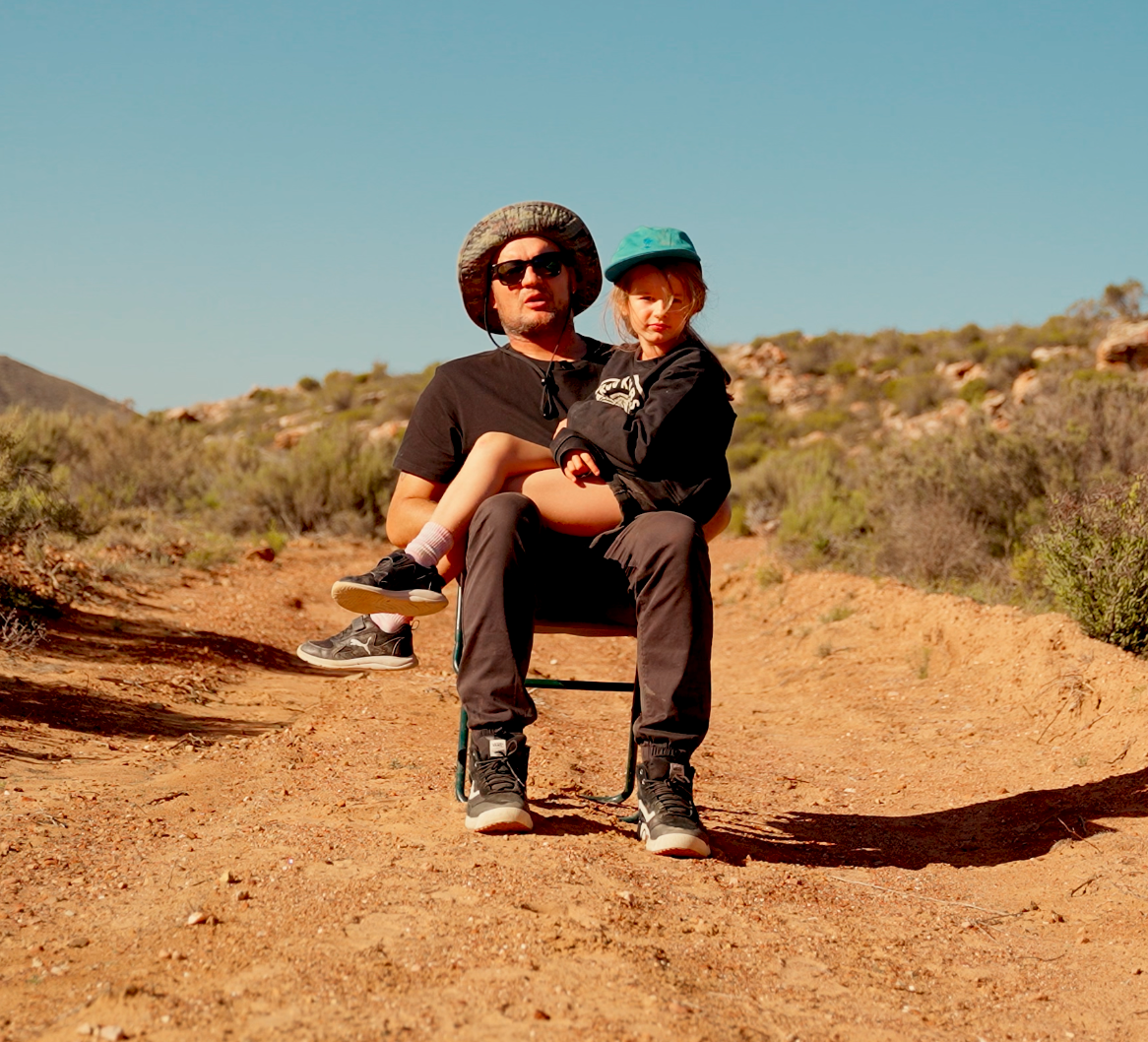 Girl sitting on her dads lap in a rough terrain