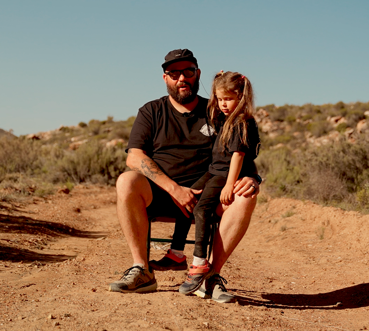 Girl sitting on her dads lap in a rough terrain