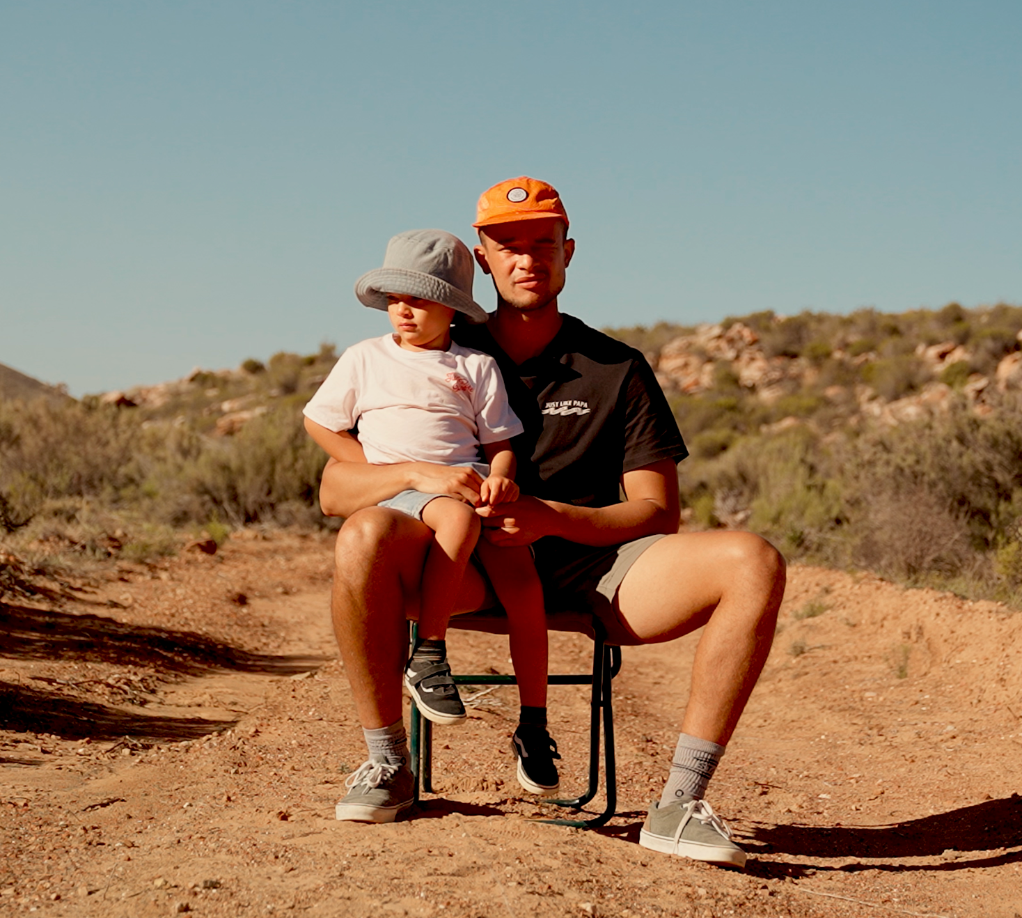 Boy sitting on his dads lap in a rough terrain